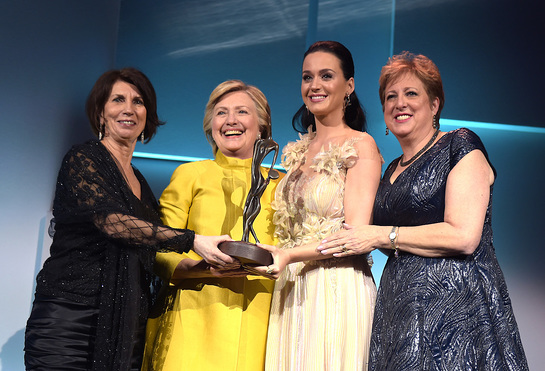 Pamela Fiori, Hillary Clinton, Katy Perry, and Caryl Stern speak on stage during the 12th annual UNICEF Snowflake Ball Pamela Fiori, Hillary Clinton, Katy Perry, and Caryl Stern speak on stage during the 12th annual UNICEF Snowflake Ball