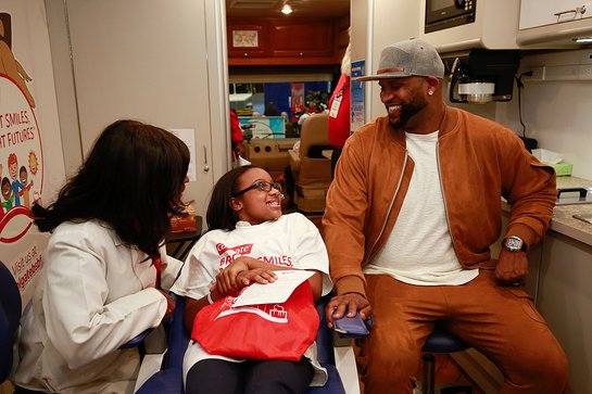 C.C. Sabathia, right, listens as Colgate Bright Smiles, Bright Futures dental coordinator Dr. Dominique Juste, left, shares oral health tips with P.S. 129 student Reina Copeland