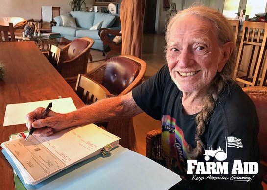 Farm Aid President Willie Nelson signs 2018 grant checks from his kitchen table