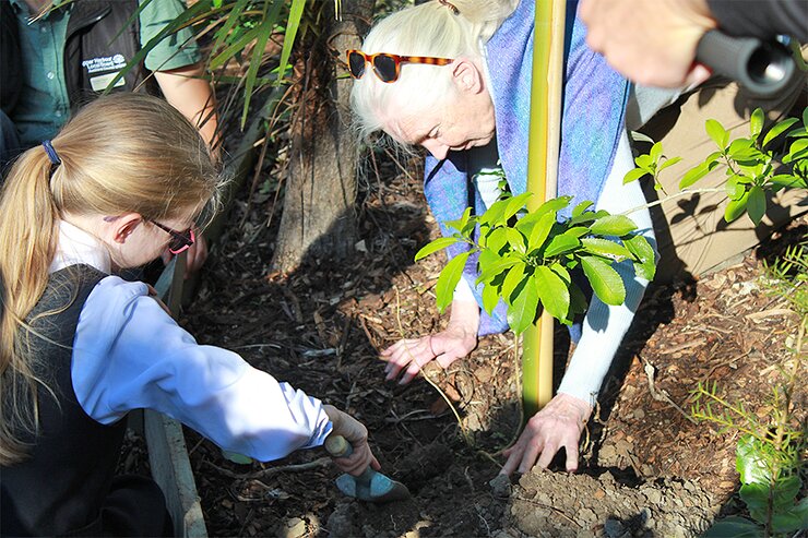 Jane and a student planting a tree