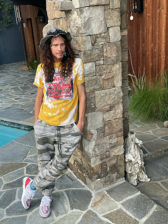 Steven Tyler wearing upcycled T-shirt from Citizen-T featuring art from Brian Fox, benefiting Janie's Fund.