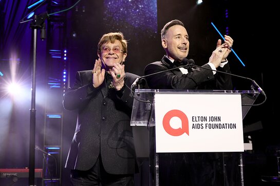 Elton John and David Furnish speak onstage at the Elton John AIDS Foundation's 32nd Annual Academy Awards Viewing Party