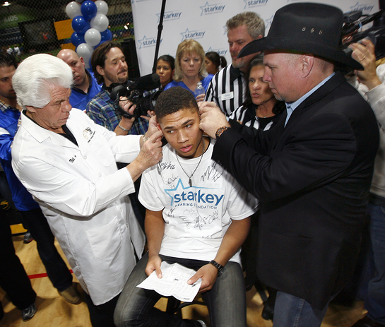 Garth Brooks assists Bill Austin, CEO and Founder, Starkey Hearing Foundation, fit an Indiana teen with digital, custom made hearing aids. Garth Brooks assists Bill Austin, CEO and Founder, Starkey Hearing Foundation, fit an Indiana teen with digital, custom made hearing aids.