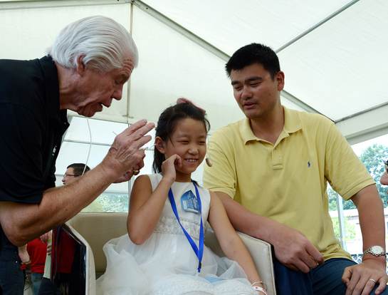 Girl receives the gift of hearing with Bill Austin, Founder, Starkey Hearing Foundation (left) and NBA Legend Yao Ming (right)