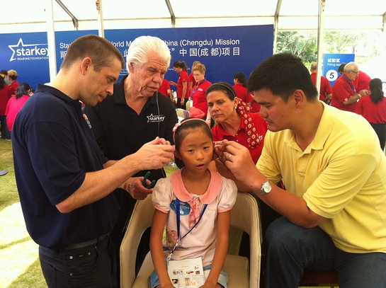 Child is fit by David Shoemaker, CEO, NBA China; Bill and Tani Austin, Co-Founders, Starkey; and NBA Legend Yao Ming. 