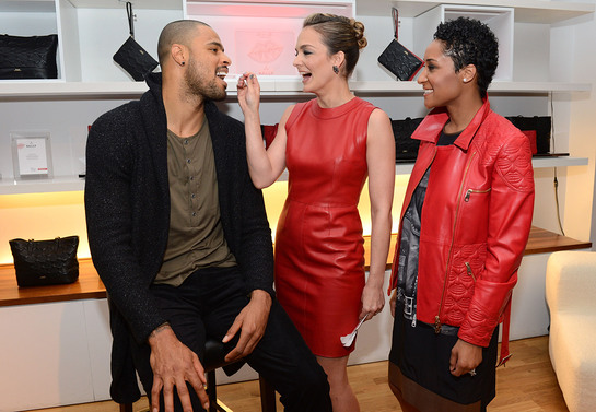 Tyson Chandler getting his cheek swabbed by DKMS Delete Blood Cancer co-founder Katharina Harf and wife, Kimberly, wearing Bally Lips for Life Collection