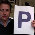 Hugh Grant Holds A Purple P For Charity
