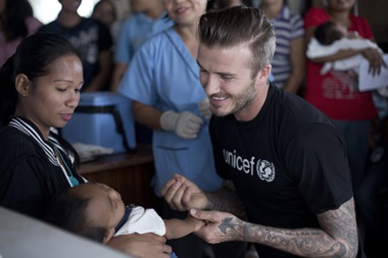 In Tanauan, Philippines, UNICEF Goodwill Ambassador David Beckham prepares to administer a dose of oral polio vaccine to an infant