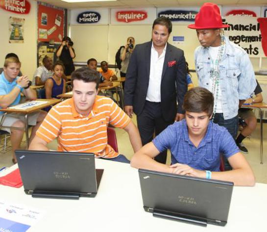EverFi Co-Founder Ray Martinez and Pharrell Williams observe students as they engage with EverFi's digital learning courses