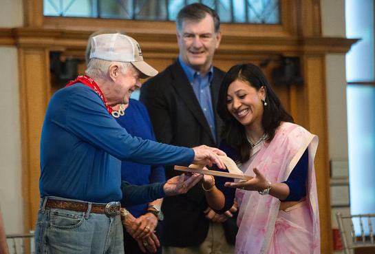 Former President Jimmy Carter passes a symbolic wooden trowel to Habitat for Humanity Nepal representative Sushma Shrestha