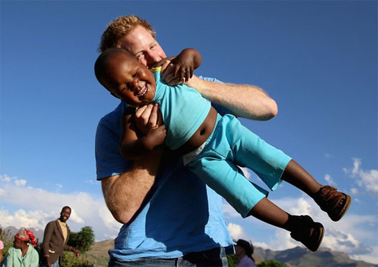 Prince Harry swings a child in the air in Lesotho