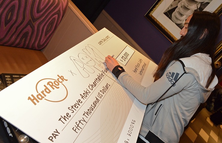 Steve Aoki signs the $50,000 check to the Steve Aoki Charitable Fund, presented by Hard Rock International