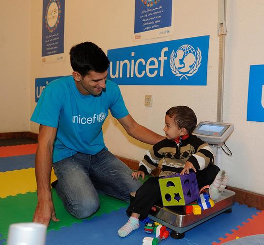 Novak Djokovic plays with a boy at the UNICEF-supported child friendly space in Belgrade